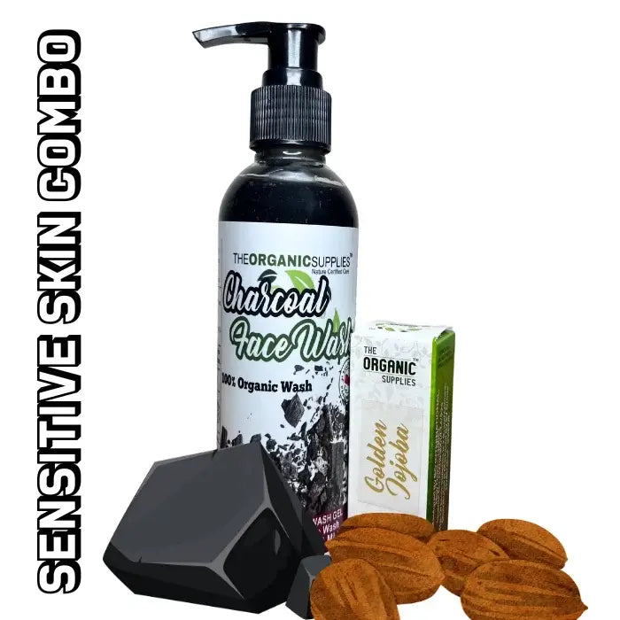 A glass bottle labeled "The Organic Supplies Charcoal Face Wash" and "GOLDEN JOJOBA OIL," along with pieces of charcoal and jojoba seeds, features the label "a sensitive skin combo."
