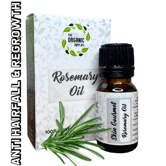 A glass dropper bottle of "Rosemary Essential Oil" with a black and white label sits on a white background, next to a small, square cardboard box containing "Rosemary Oil" and some fresh rosemary leaves. 