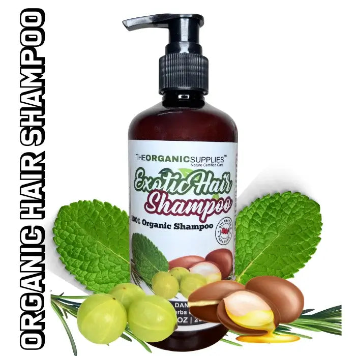 An image featuring a glass bottle of 'Exotic Hair Shampoo' from the brand 'The Organic Supplies.' The shampoo is artfully surrounded by fresh mint leaves, amla (Indian gooseberry), tea tree leaves, and argan, highlighting the natural and invigorating ingredients.